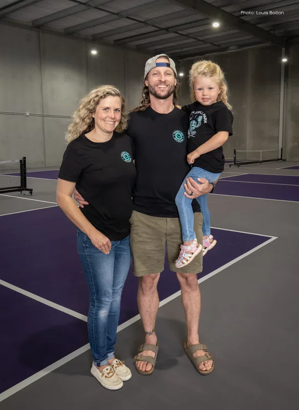 Family standing together beside the indoor pickleball courts